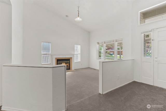 unfurnished living room featuring dark colored carpet and high vaulted ceiling