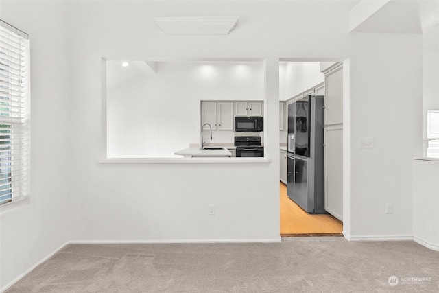 kitchen with gray cabinets, black appliances, sink, and light colored carpet