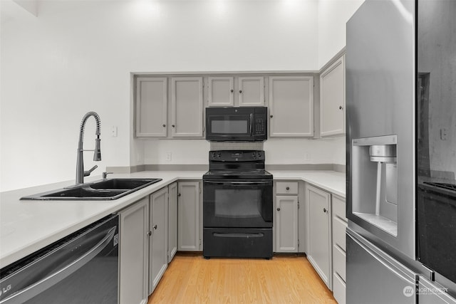 kitchen featuring gray cabinets, black appliances, sink, and light hardwood / wood-style floors