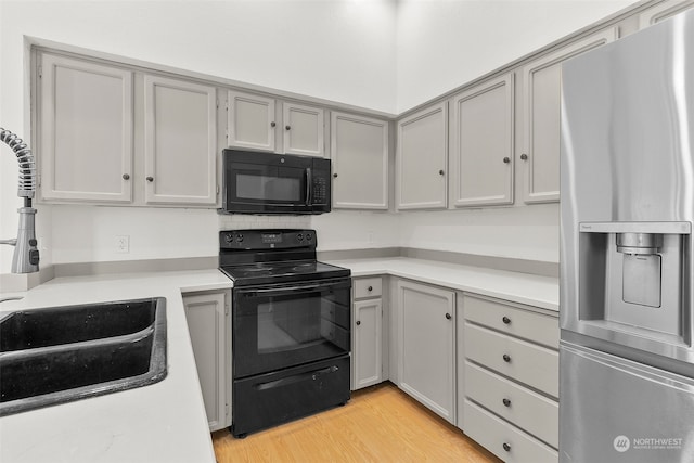 kitchen featuring gray cabinetry, black appliances, sink, and light hardwood / wood-style flooring