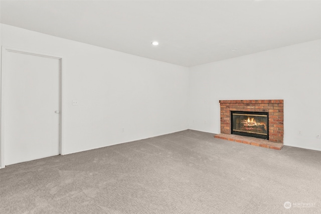 unfurnished living room featuring a brick fireplace and light colored carpet