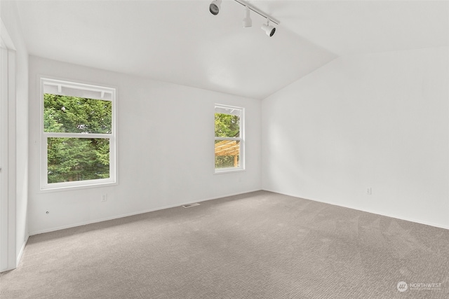 spare room with track lighting, lofted ceiling, and carpet flooring