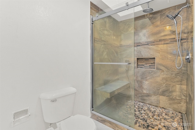 bathroom featuring a shower with door and toilet