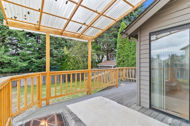 wooden terrace featuring a yard and a fire pit