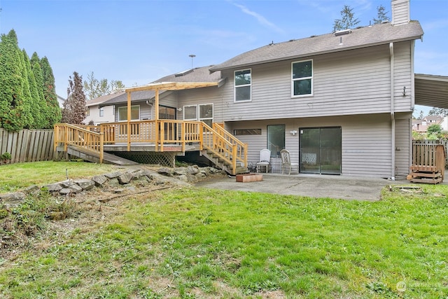 back of property with a yard, a wooden deck, and a patio area