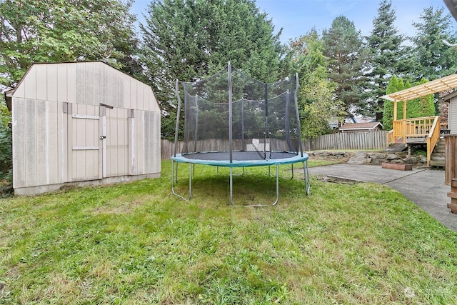 view of yard with a trampoline, a storage shed, and a deck