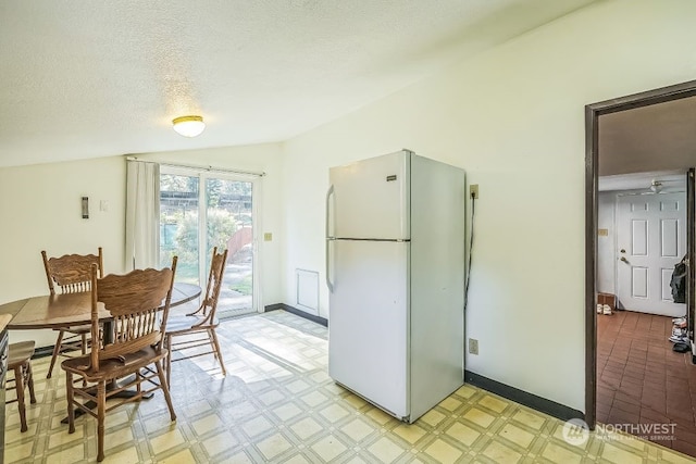 kitchen featuring white fridge, a textured ceiling, and lofted ceiling