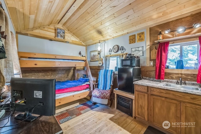 bedroom featuring wood ceiling, light wood-type flooring, vaulted ceiling with beams, black refrigerator, and sink