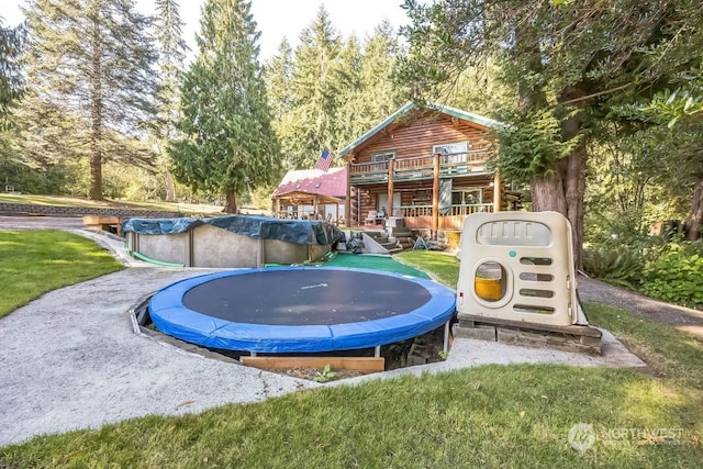 exterior space with a yard, a trampoline, and a pool side deck