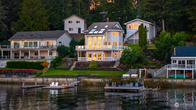 back of property with a water view and a balcony