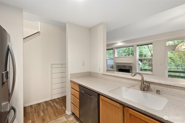 kitchen featuring a sink, stainless steel appliances, plenty of natural light, and a stone fireplace