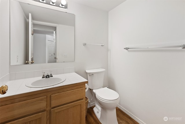 bathroom with baseboards, toilet, wood finished floors, and vanity