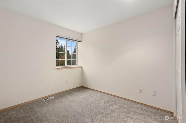 carpeted empty room featuring baseboards and visible vents