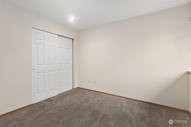 unfurnished bedroom featuring baseboards, carpet floors, and a closet