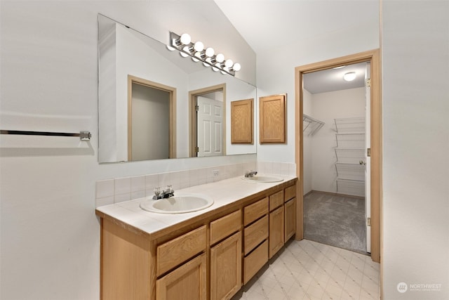 full bathroom featuring tile patterned floors, double vanity, a walk in closet, and a sink