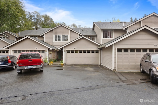 view of front of home with a garage, driveway, and roof with shingles