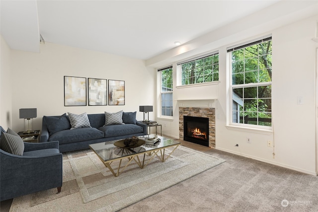 living area with a stone fireplace, baseboards, and carpet