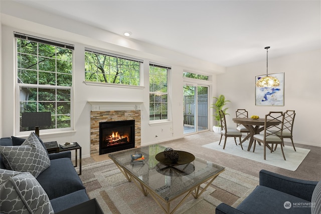 carpeted living room featuring a stone fireplace and a healthy amount of sunlight