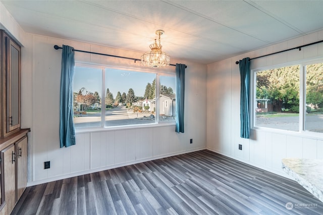 unfurnished dining area featuring a chandelier, dark hardwood / wood-style flooring, and a healthy amount of sunlight