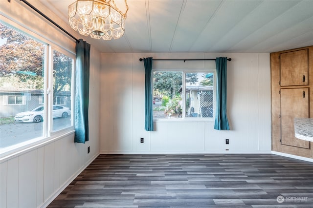 empty room featuring wood walls, dark hardwood / wood-style floors, and a chandelier