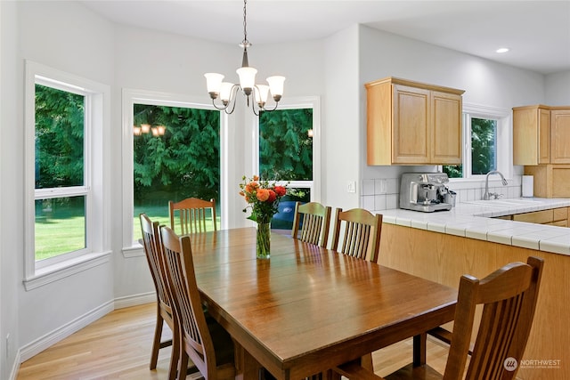 dining space with a chandelier, light hardwood / wood-style floors, and sink