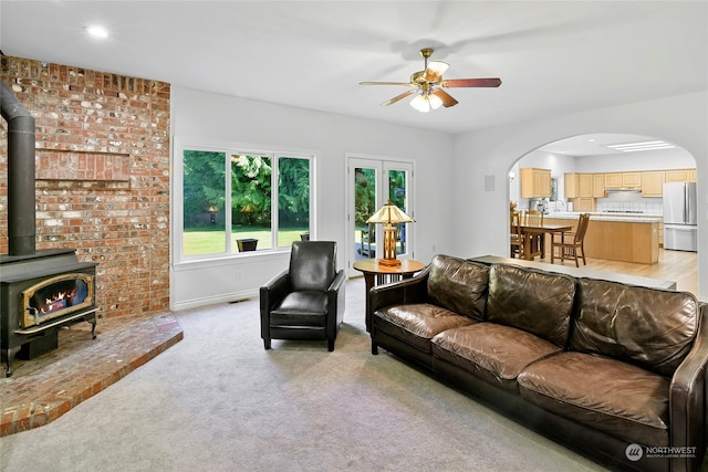 carpeted living room featuring ceiling fan and a wood stove