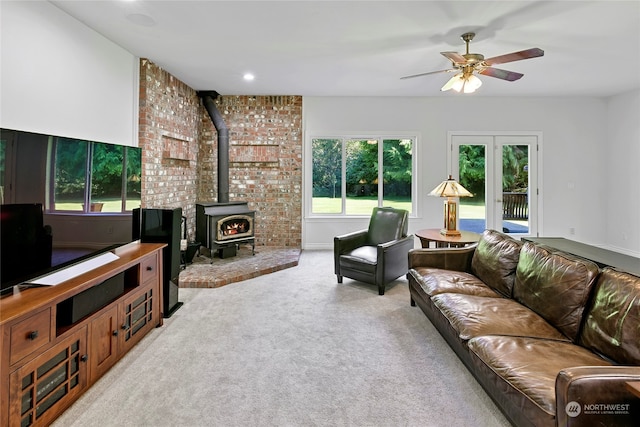 living room featuring light carpet, a wood stove, and ceiling fan