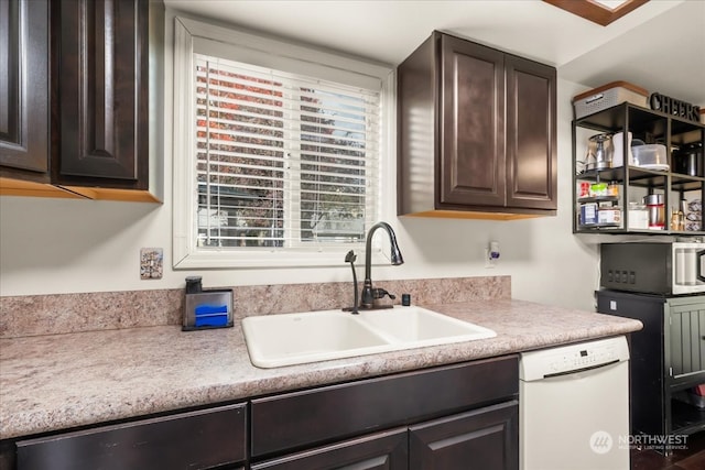 kitchen featuring dark brown cabinets, white dishwasher, and sink