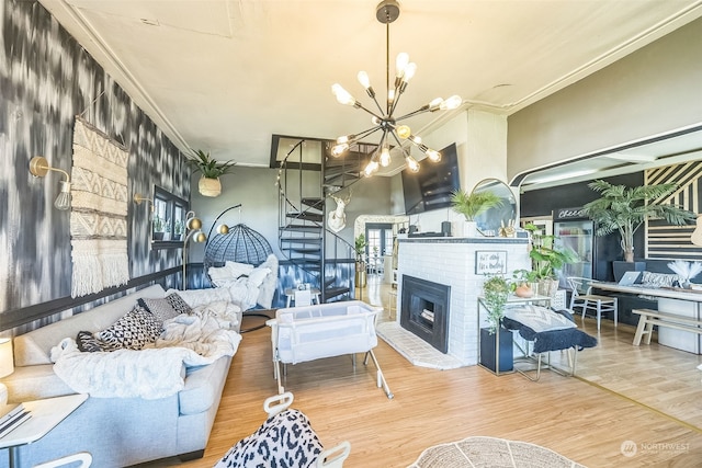 living room with a brick fireplace, a chandelier, crown molding, hardwood / wood-style floors, and a wealth of natural light