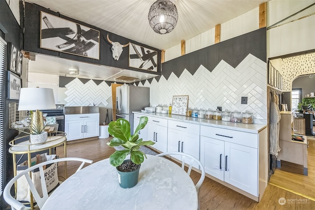 kitchen featuring decorative backsplash, white cabinets, hardwood / wood-style floors, and stainless steel fridge