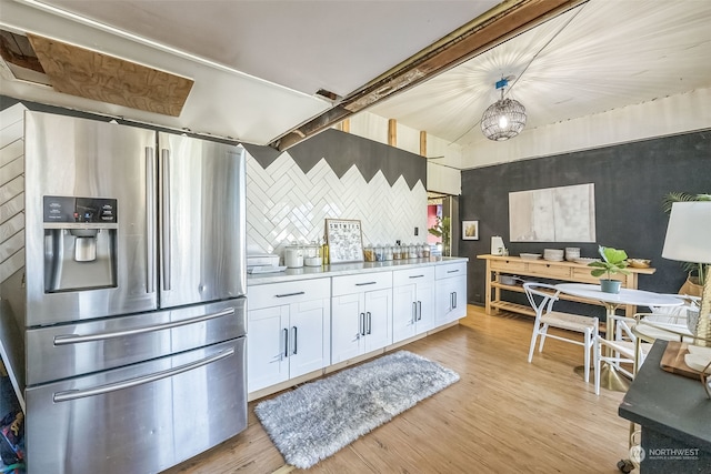 kitchen featuring light wood-type flooring, tasteful backsplash, white cabinets, hanging light fixtures, and stainless steel fridge with ice dispenser