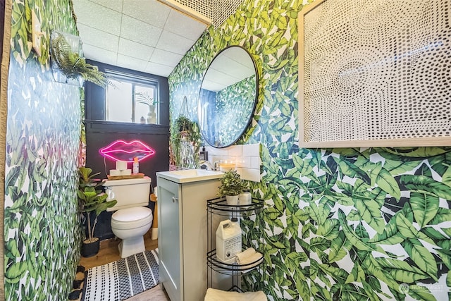 bathroom with vanity, a drop ceiling, hardwood / wood-style floors, and toilet