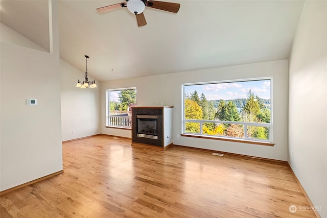 unfurnished living room featuring ceiling fan with notable chandelier, light hardwood / wood-style flooring, and high vaulted ceiling