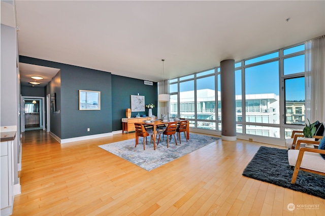 dining space with plenty of natural light, a wall of windows, and light wood-type flooring