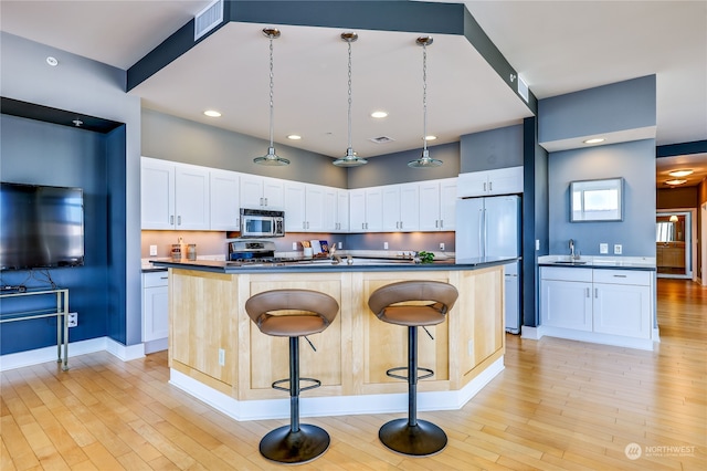 kitchen featuring stainless steel appliances, white cabinets, a kitchen island, and a kitchen breakfast bar