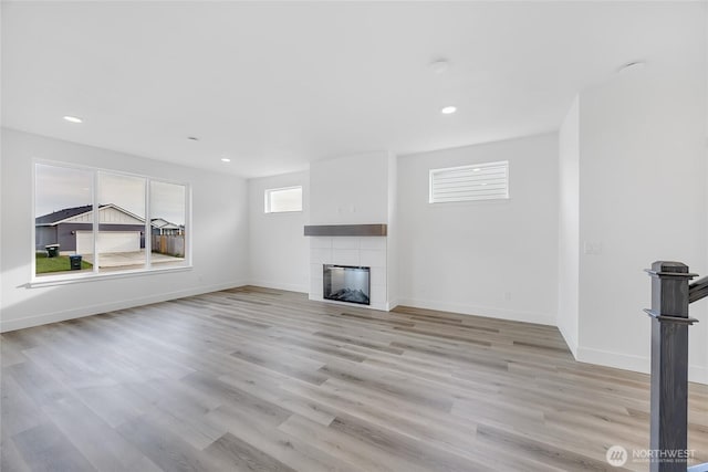 unfurnished living room with light wood-type flooring and a tile fireplace