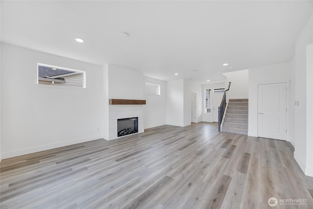 unfurnished living room featuring light hardwood / wood-style floors and a tiled fireplace