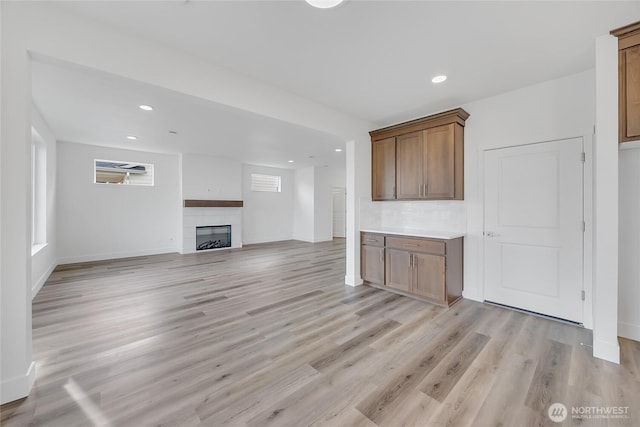 unfurnished living room with a tiled fireplace and light hardwood / wood-style floors