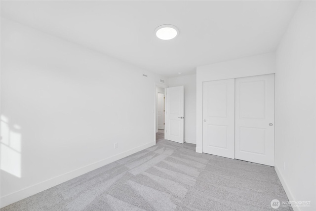 unfurnished bedroom featuring light carpet and a closet