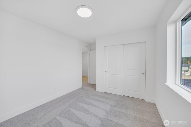 unfurnished bedroom featuring a closet and light colored carpet