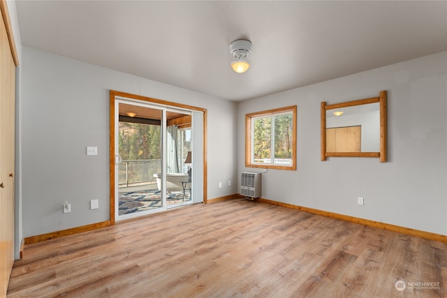 spare room with heating unit and light hardwood / wood-style flooring