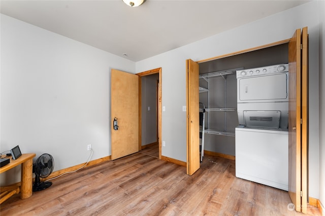 clothes washing area with hardwood / wood-style floors and stacked washer and dryer