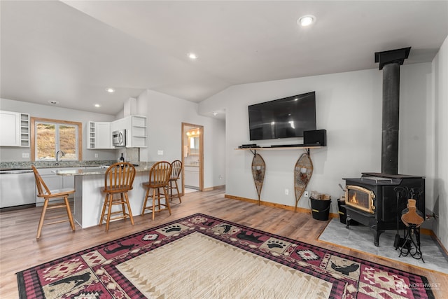 living room featuring lofted ceiling, light wood-type flooring, and a wood stove