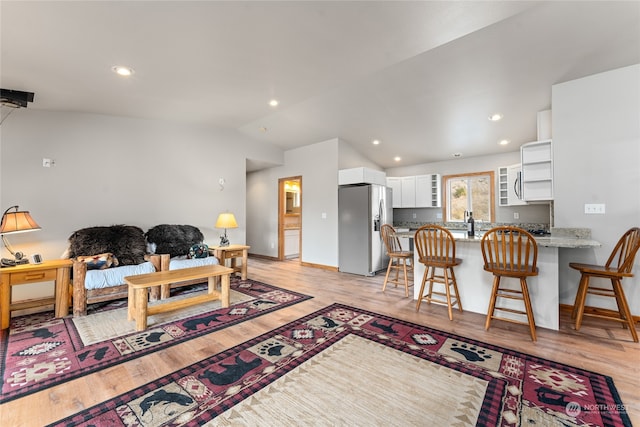 living room featuring light hardwood / wood-style floors and vaulted ceiling