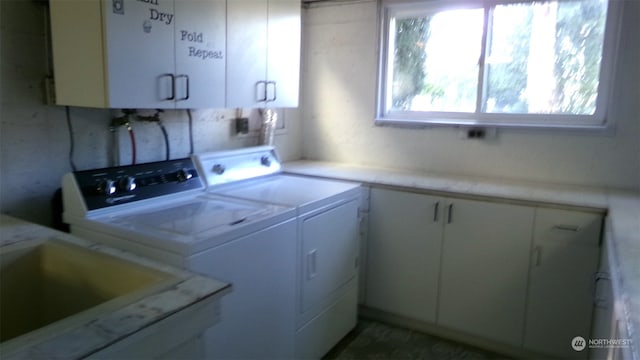 laundry area with washing machine and clothes dryer and cabinets