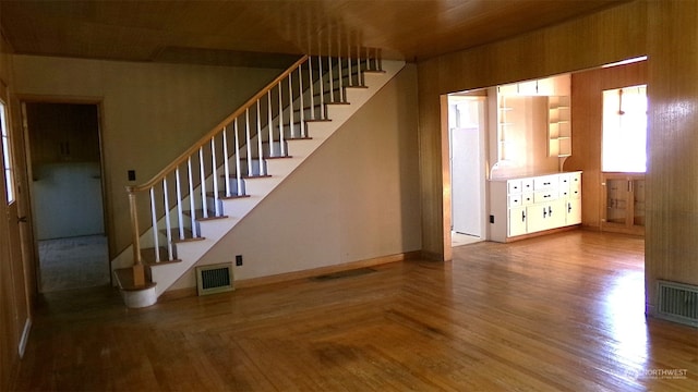 unfurnished living room featuring wooden walls and hardwood / wood-style floors