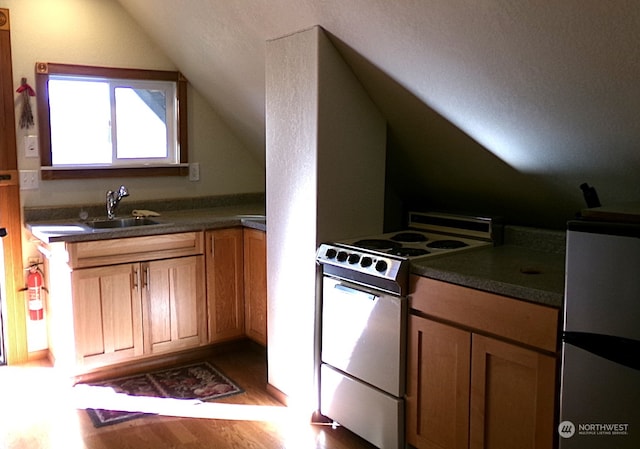 kitchen featuring stainless steel refrigerator, wood-type flooring, vaulted ceiling, sink, and white range oven