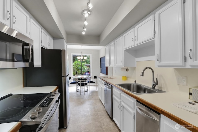 kitchen with appliances with stainless steel finishes, sink, white cabinets, a chandelier, and hanging light fixtures