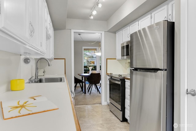 kitchen with stainless steel appliances, sink, light tile patterned floors, and white cabinets