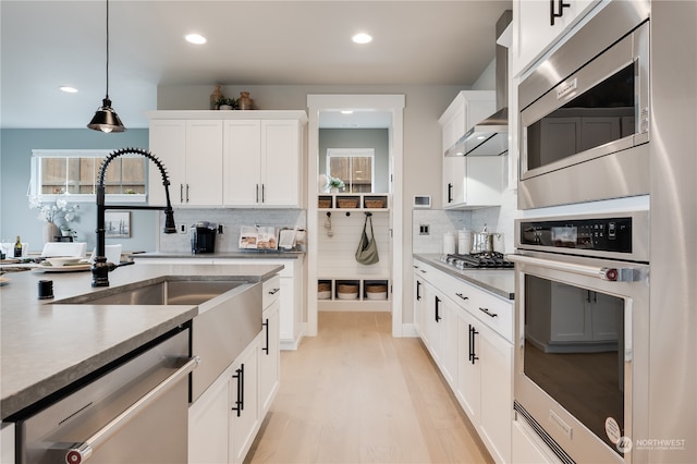 kitchen with stainless steel appliances, hanging light fixtures, decorative backsplash, and white cabinetry